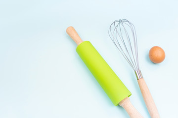 Kitchen utensils and baking accessories on blue background with copy space. Rolling pin and whisk for cooking. Set for mock ups and bakery design. Flat lay.
