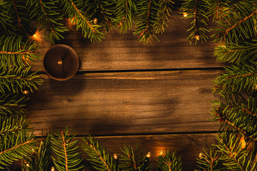 Christmas background with fir branches, lights and candle, top view and copy space for text, christmas card, invitation or frame