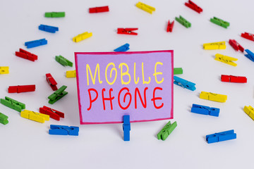 Conceptual hand writing showing Mobile Phone. Concept meaning A handheld device used to send receive calls and messages Colored clothespin papers empty reminder white floor office