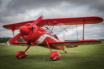 Beautiful red vintage airplane standing on the green grass near the airport field. Pitts Special...