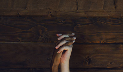 Hands of a multiracial couple of women on a wooden background