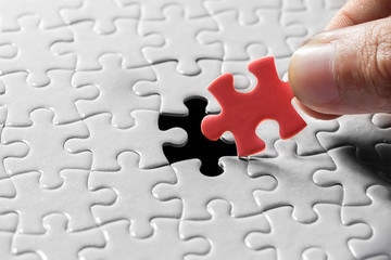 Hand holding piece of blank jigsaw puzzle