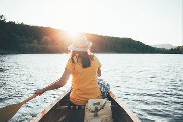 Rear view of woman paddling canoe on the sunset lake