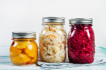 Fermented vegetables in jars. Sauerkraut, pickled beets and pickled squash on a light wooden...