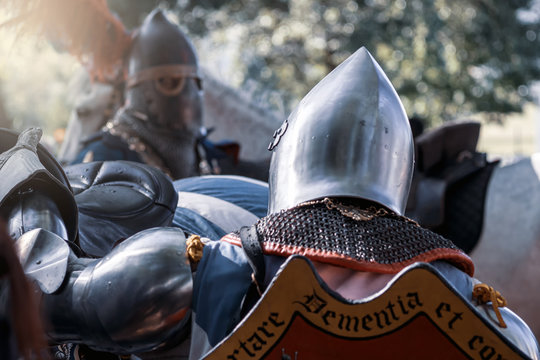 A knight in a helmet with a feather next to his horse. Reconstruction of the Middle Ages