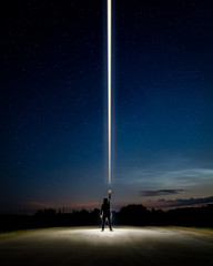 Man standing in the middle of the road with the light beam from his hand