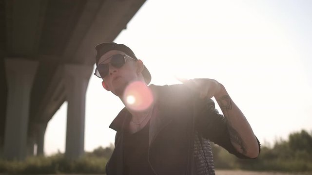 Caucasian young man looking at camera. Handsome stylish man. Sunny day. Portrait of a tough guy in a black leather jacket. Contemporary dance. Krump. Hip hop style, listening to music. Closeup