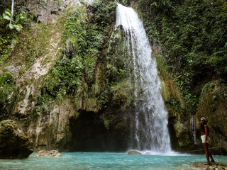Naklejka premium Woman alone in deep forest waterfall from mountain gorge at hidden tropical jungle in Cebu Island in Philippines