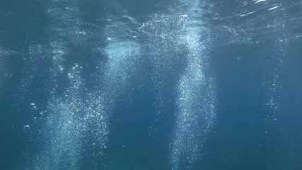 Slow motion of air bubbles floating from sea bottom to the water surface. Air bubbles in the blue water