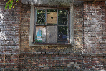 Fototapeta na wymiar Vintage old window with lattice metal bars on the wall facade