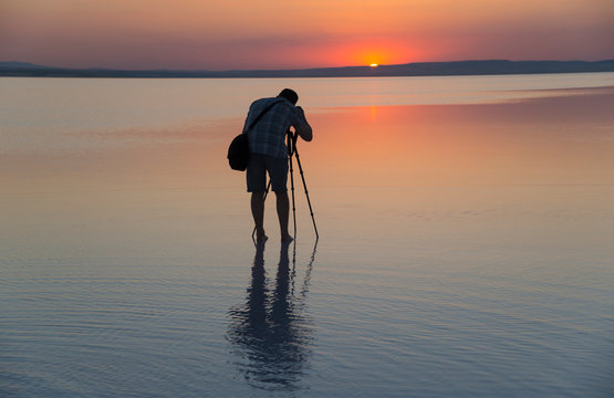 Photographer takes pictures of sunset while standing in water