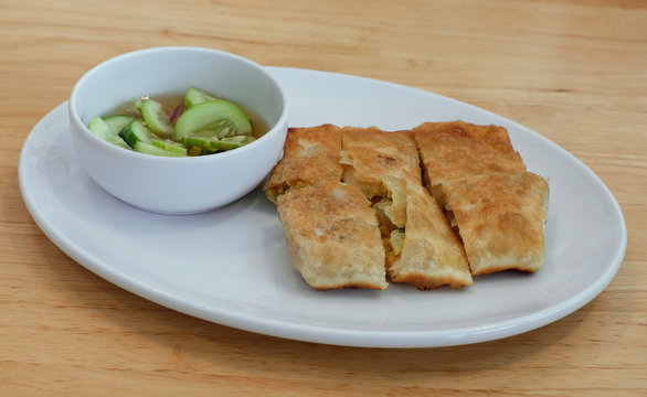 mataba chicken roti with spicy sauce on wood table