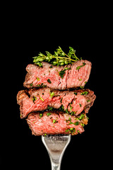 Sliced beef steak from grill on a fork with herbs.