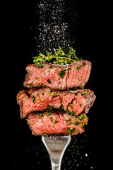 Sliced beef steak from grill on a fork. Salt is strewing from above - obrazy, fototapety, plakaty