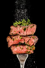 Schilderijen op glas Sliced beef steak from grill on a fork. Salt is strewing from above © PawelG Photo