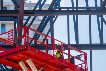 Professional installation work on a construction building site. Assemblers perform high-altitude installation works on the telescopic  boom lifts platforms. Installation of huge steel beams.