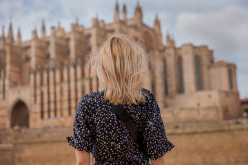Blond woman tourist looking towards Cathedral La Seu at Palma de Mallorca. Mallorca island, Spain