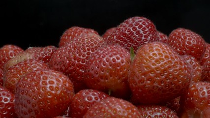 Fresh strawberries isolated on black background. Rotation 360 degrees, closeup. 4K - 50fps