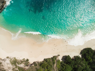 Aerial drone view of beach with waves and people at Karang Dawa, Manta Bay or Kelingking Beach on Nusa Penida Island, Bali, Indonesia - obrazy, fototapety, plakaty