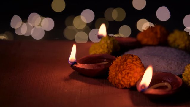 Burning Oil Lamps. Oil lamps lit with traditional decorative flower rangoli on a wooden surface with bokeh in black background with copy space.