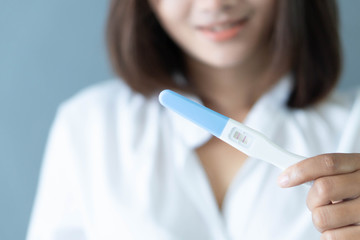 Closeup woman hand holding pregnancy test with happy moment, health care concept, selective focus