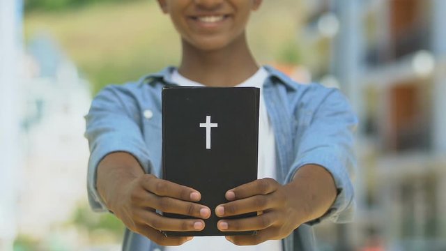 Teen boy holding bible, spiritual development, religious education since youth