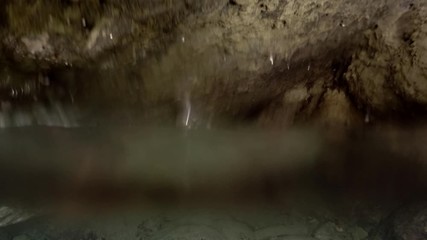 Plastic pollution, Underwater split level. A plastic bottle floats on the surface of the water inside a cave. Underwater shots. Plastic bottle in Mediterranean Sea, Europe.