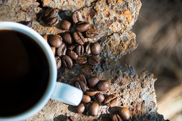 Cup of coffee and coffee beans closeup on iron rusty background