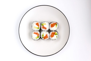 Fresh prepared sushi rolls with avocado, red fish salmon and whit cheese filadelfia in black nori on white plate. Top view