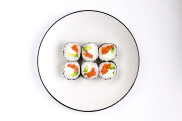 Fresh prepared sushi rolls with avocado, red fish salmon and whit cheese filadelfia in black nori on white plate. Top view