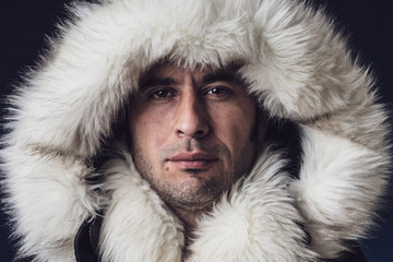 Close up portrait of a white man dressed with an eskimo jacket  looking at the camera - obrazy, fototapety, plakaty