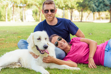 Couple lying in the park while having fun with the dog.happy family concept