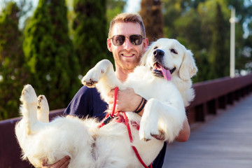 young and beautiful man holding his dog in his arms with love and playing with him
