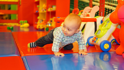 Fototapeta na wymiar Two years old child boy play in indoor kindergarten playground.