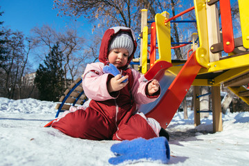 little baby plays in the playground in winter