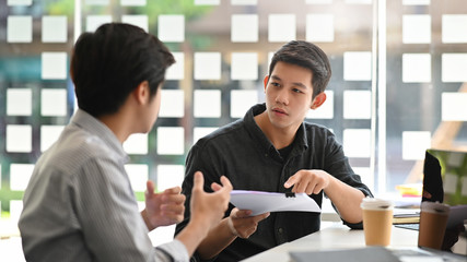 Fototapeta premium Asian young man consulting with paper document on modern office.