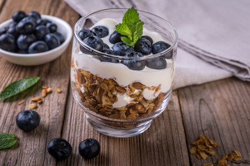 granola with yogurt and fresh blueberries in a glass  on wooden background