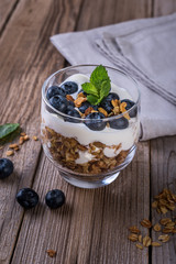 granola with yogurt and fresh blueberries in a glass  on wooden background