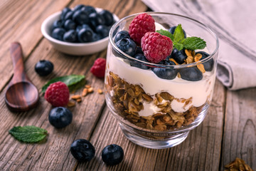 granola with yogurt and fresh blueberries in a glass  on wooden background