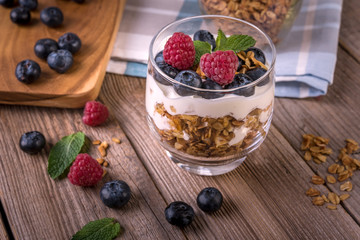 granola with yogurt and fresh blueberries in a glass  on wooden background