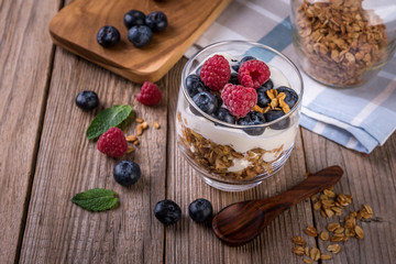 granola with yogurt and fresh blueberries in a glass  on wooden background