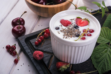 Healthy greek yogurt in a ceramic bowl with fresh berries and chia seeds