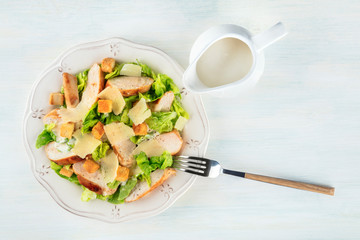 Chicken Caesar salad, shot from the top with a sauce jug and a place for text