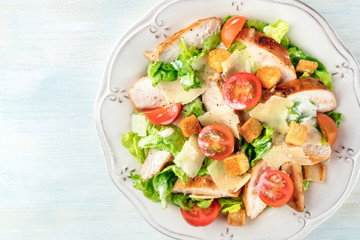 A close-up of a chicken Caesar salad, shot from above with copy space