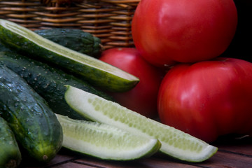 tomatoes and cucumbers next to a wicker basket