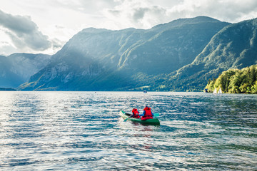Couple paddling a kayak. Wonderful summer scene of Bohinj lake, Triglav National park. Sunny morning view of Julian Alps, Slovenia. Concept for adventure, travel, action, lifestyle.