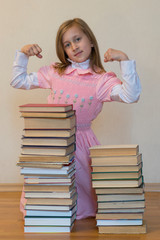 Concept The power of knowledge. A girl with a pile of books shows her strength. Education concept. copy space. vertical photo