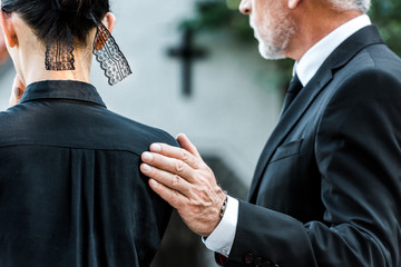 cropped view of man touching woman on funeral - obrazy, fototapety, plakaty