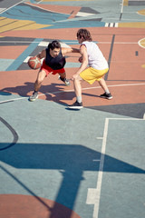 Top view image of two young sportsmen playing basketball on playground in morning.