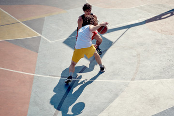 Top view of two athletes men playing basketball on playground in morning.